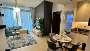 Een moderne woonkamer met een bank, salontafel en een eethoek met een tafel gedekt voor vier personen.