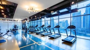 Een sportschool met loopbanden en trainingsapparatuur, grote ramen met uitzicht op de stad, en een modern design.