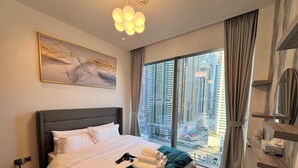Een moderne hotelkamer met een groot bed, uitzicht over de stad en een bijzondere plafondlamp.