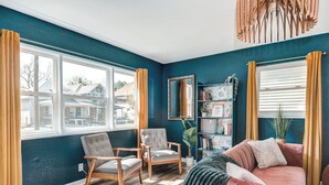 Un salon chaleureux avec un mur de couleur turquoise, deux fauteuils, un canapé et une bibliothèque.