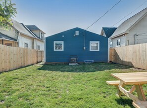 A backyard with a wooden fence, a blue house, and a picnic table.
