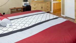 Een slaapkamer met een bed, een plafondventilator, een televisie, een dressoir en een spiegel.