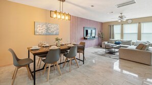 A modern living room with a dining area, a flat-screen TV, and a ceiling fan. - 🎁 Holiday Savings! Modern 4-Bedroom Home in Katy• Game Area • Crib • Firepit (Katy)