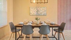 A dining area with a rectangular table set for six, surrounded by six chairs, a vase with flowers, and a painting of flowers on the wall. - 🎁 Holiday Savings! Modern 4-Bedroom Home in Katy• Game Area • Crib • Firepit (Katy)