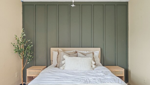 A bedroom with a bed, a nightstand, a potted plant, and a wall with vertical panels. - 🎁 Holiday Savings! Modern 4-Bedroom Home in Katy• Game Area • Crib • Firepit (Katy)