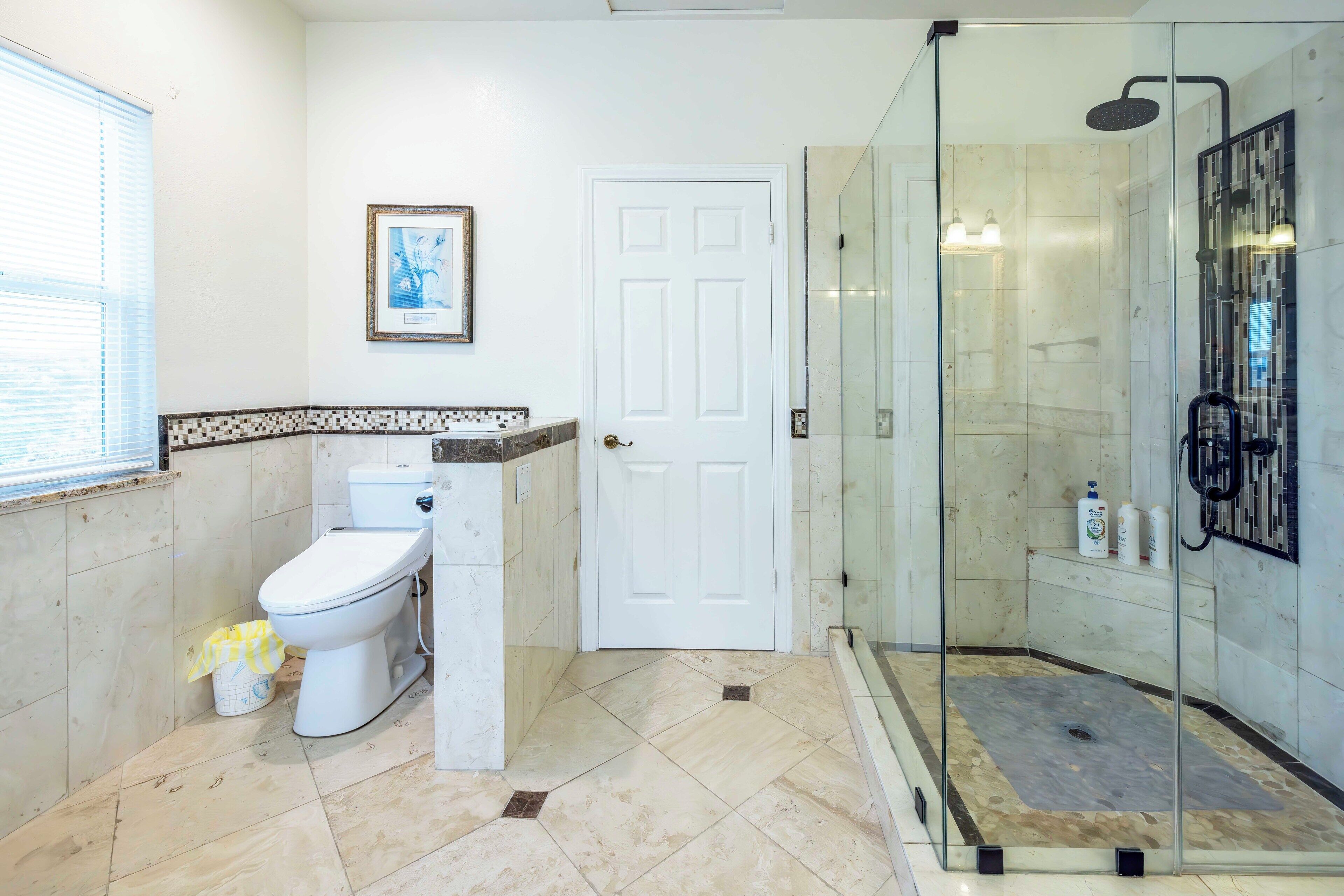 Un bagno con il water, una doccia con pareti in vetro e una porta bianca.