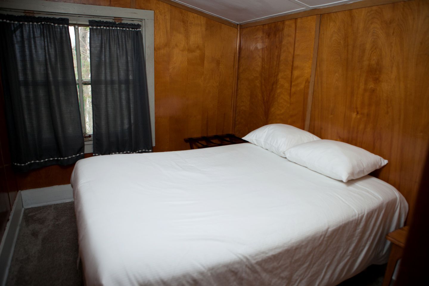 A single bed with white bedding in a room with wooden paneling.