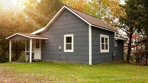 A two-story house with a covered porch, a front door, and a small window on the side. - Cozy Cabin Overlooking Chequamegon Bay in Ashland, Wisconsin (Ashland)