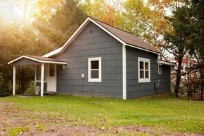 A two-story house with a covered porch, a front door, and a small window on the side. - Cozy Cabin Overlooking Chequamegon Bay in Ashland, Wisconsin (Ashland)