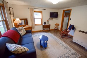 A living room with a sofa, a small table, a television, and a heater. - Cozy Cabin Overlooking Chequamegon Bay in Ashland, Wisconsin (Ashland)