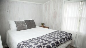 A bed with a patterned blanket, pillows, and a nightstand with a plant. - Cozy Cabin Overlooking Chequamegon Bay in Ashland, Wisconsin (Ashland)