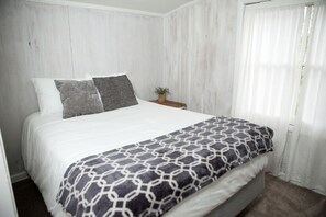 A bed with a patterned blanket, pillows, and a nightstand with a plant. - Cozy Cabin Overlooking Chequamegon Bay in Ashland, Wisconsin (Ashland)