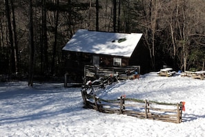 A cabin with a snow-covered roof, surrounded by a wooden fence and picnic tables. - Inviting Cabin Retreat with a Private Hot Tub in Bryson City, North Carolina (Bryson City)