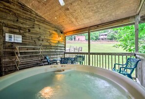 Un bain à remous dans un chalet en bois, avec vue sur une cour verdoyante.