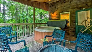 A wooden cabin with a hot tub, outdoor seating, and a view of the forest. - Inviting Cabin Retreat with a Private Hot Tub in Bryson City, North Carolina (Bryson City)