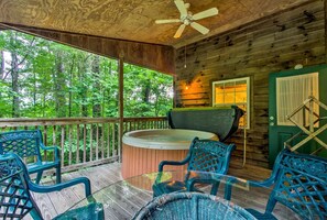Een houten chalet met een jacuzzi, terras en uitzicht op het bos.