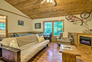 A cozy living room with a wooden ceiling, a sofa, a chair, a fireplace, and a bicycle mounted on the wall. - Inviting Cabin Retreat with a Private Hot Tub in Bryson City, North Carolina (Bryson City)