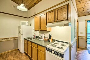 Cocina compacta con armarios de madera, un refrigerador blanco, una estufa y un microondas.