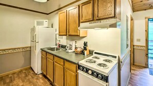 A compact kitchen with wooden cabinets, a white refrigerator, a stove, and a microwave. - Inviting Cabin Retreat with a Private Hot Tub in Bryson City, North Carolina (Bryson City)