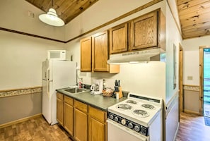 A compact kitchen with wooden cabinets, a white refrigerator, a stove, and a microwave. - Inviting Cabin Retreat with a Private Hot Tub in Bryson City, North Carolina (Bryson City)