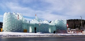 Un'imponente scultura di ghiaccio a forma di castello, con bandiere, sullo sfondo di un paesaggio innevato.