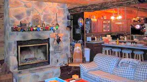 A stone fireplace, a bar area, and a checkered sofa in a rustic interior.