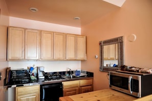 A kitchen with wooden cabinets, a stove, a microwave, and a sink.