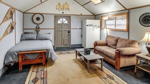 Ein gemütliches Interieur mit einem Bett, einer Couch, einem kleinen Tisch und dekorativer Wandkunst.