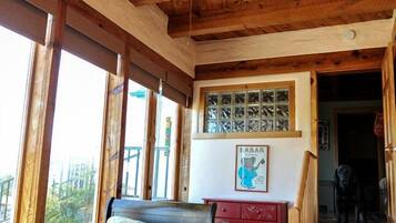 A bedroom with a bed, a ceiling fan, a dresser, and a window with a view.