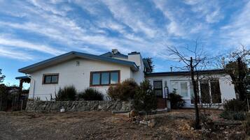 A single-story house with a sloped roof, a front porch, and a stone retaining wall.