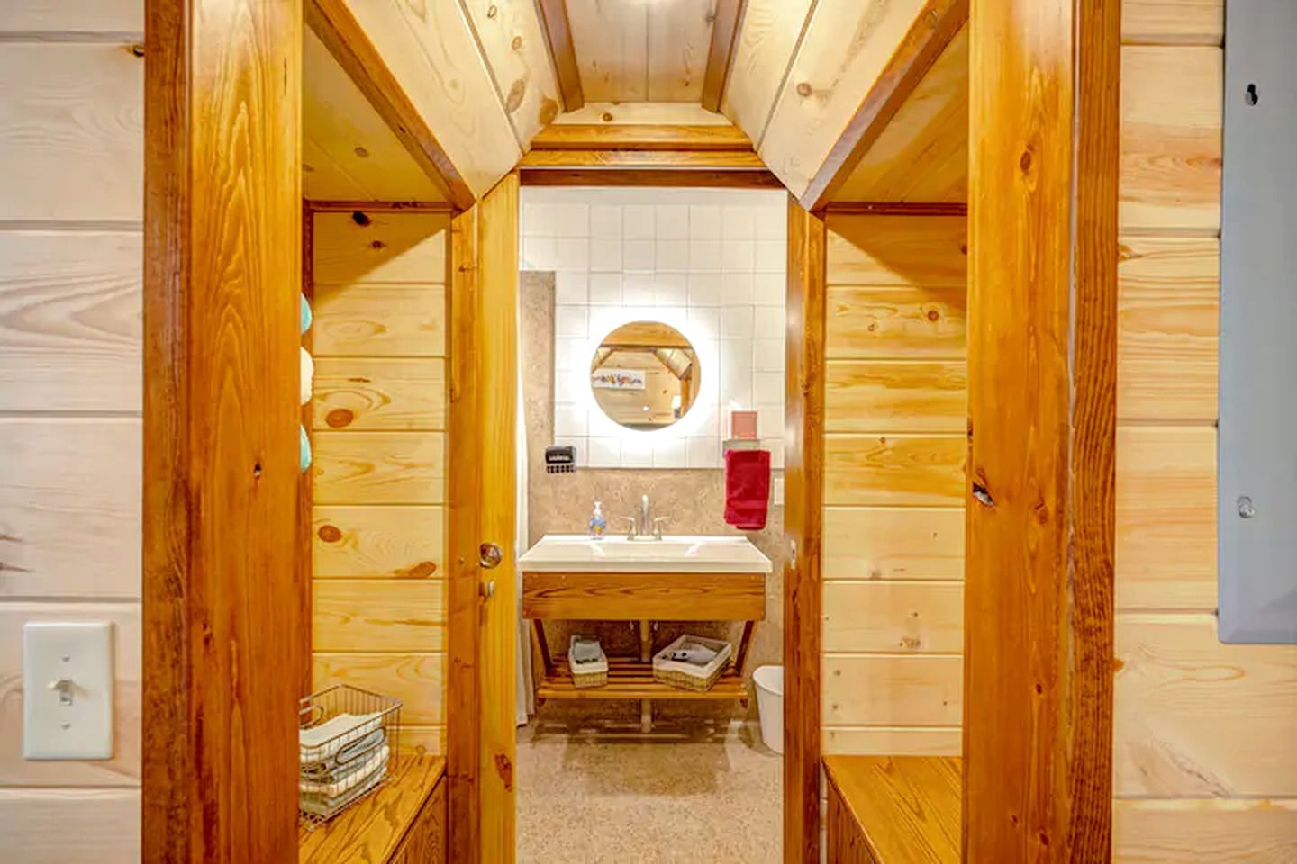 A wooden-paneled bathroom with a sink, mirror, and towel rack.