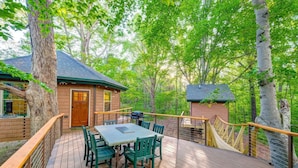 A wooden deck with a table and chairs, surrounded by trees. - Nashville Area Luxury Tree House Accommodation for a Tennessee Getaway (Greenbrier)