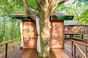 Une cabane en bois avec une terrasse, un espace douche et une fenêtre.