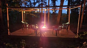 Eine Holzterrasse mit Stühlen und einer hängenden Leuchte.