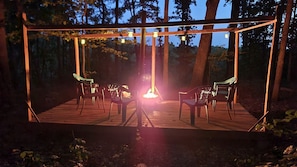 Une terrasse en bois avec des chaises et un luminaire suspendu.