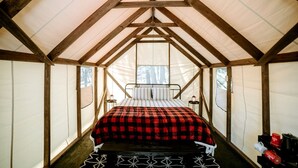 A tented room with a bed, a small table, and a window. - Glamping Safari Tent for Romantic Escapes to the Minnesota Forest (Beaver Bay)