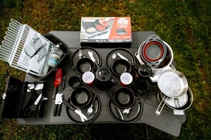 A camping setup with a portable stove, cookware, and a folding dish rack.