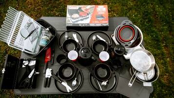 En campingutrustning som inkluderar ett portabelt campingkök, kokkärl och ett hopfällbart diskställ.