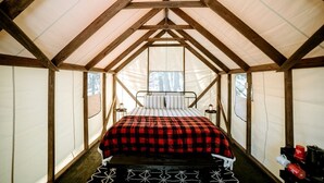 A tented room with a bed, a small table, and a window. - Glamping Safari Tent for Romantic Escapes to the Minnesota Forest (Beaver Bay)