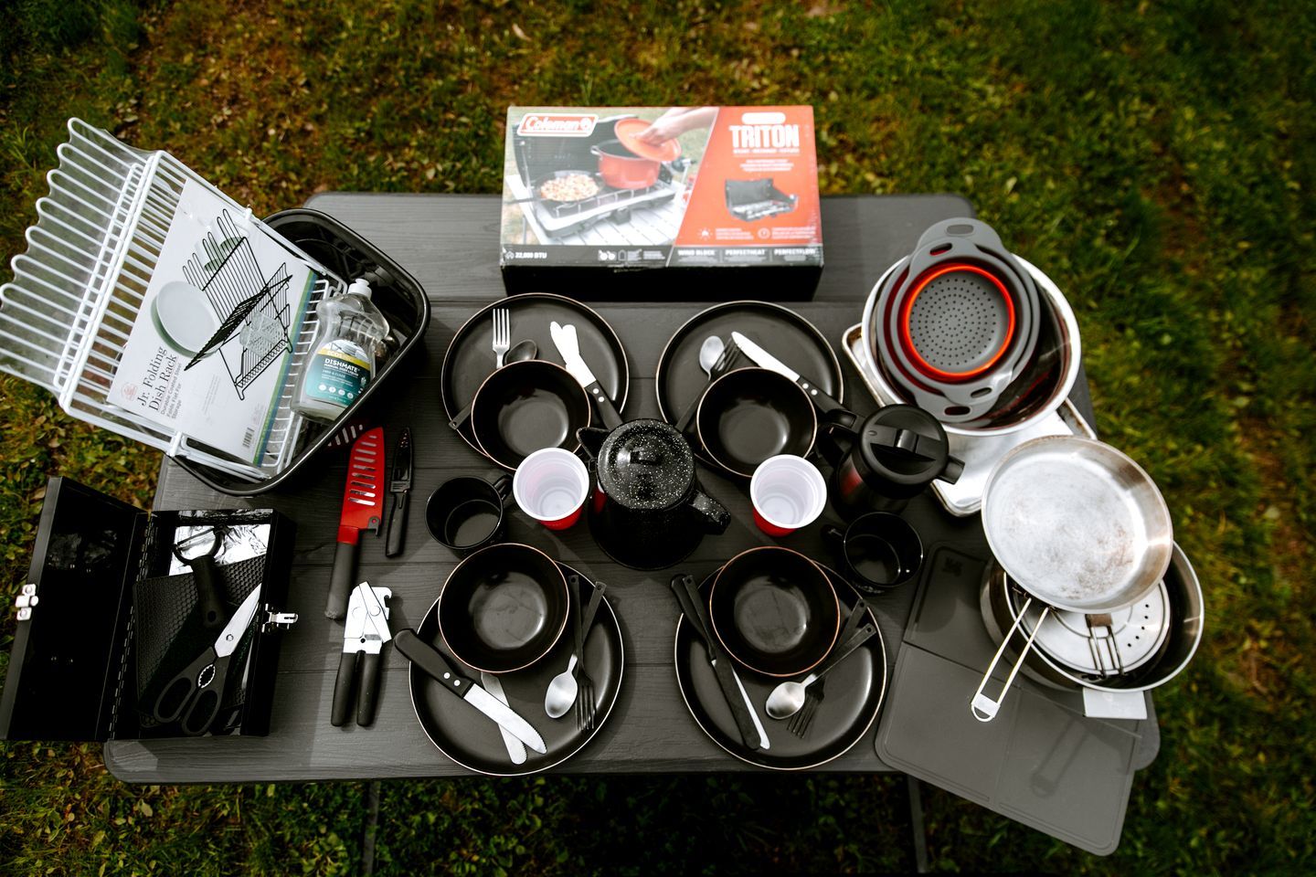 Un ensemble de camping comprenant un réchaud portable, des ustensiles de cuisine et un égouttoir pliable.