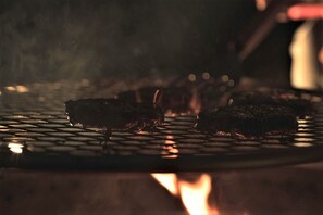 A grill with food being cooked. - Glamping Safari Tent for Romantic Escapes to the Minnesota Forest (Beaver Bay)