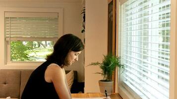A person seated at a wooden table with a window in the background.