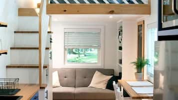 A compact living space with a loft bedroom, a dining area, and a kitchen.