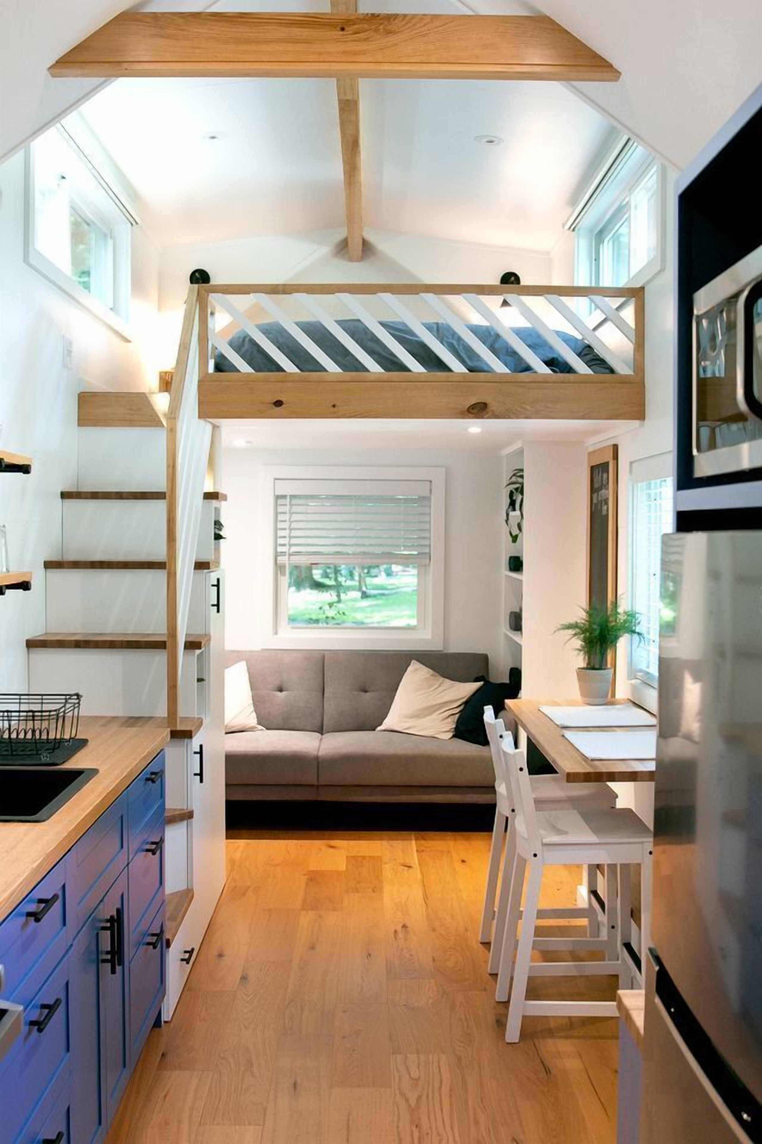 Un espacio habitable compacto con un dormitorio en loft, una zona de comedor y una cocina.