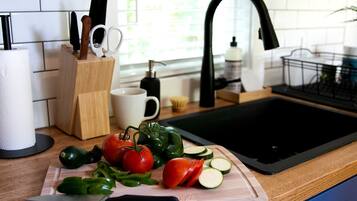 A kitchen counter with a cutting board, vegetables, and a knife.