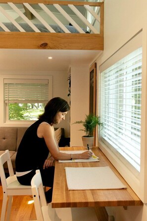 A person seated at a wooden table with a window in the background.