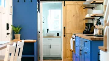 A compact kitchen with wooden cabinets, a sink, and a dining area with chairs.