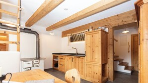 Cucina con mobili in legno, un fornello e un'area pranzo con tavolo e sedie.