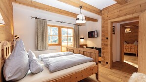 Una camera da letto in legno con un letto, una finestra con tende, una TV a parete e un armadio in legno.