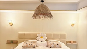 Een slaapkamer met een groot bed, een geweven plafondlamp en wandlampen.